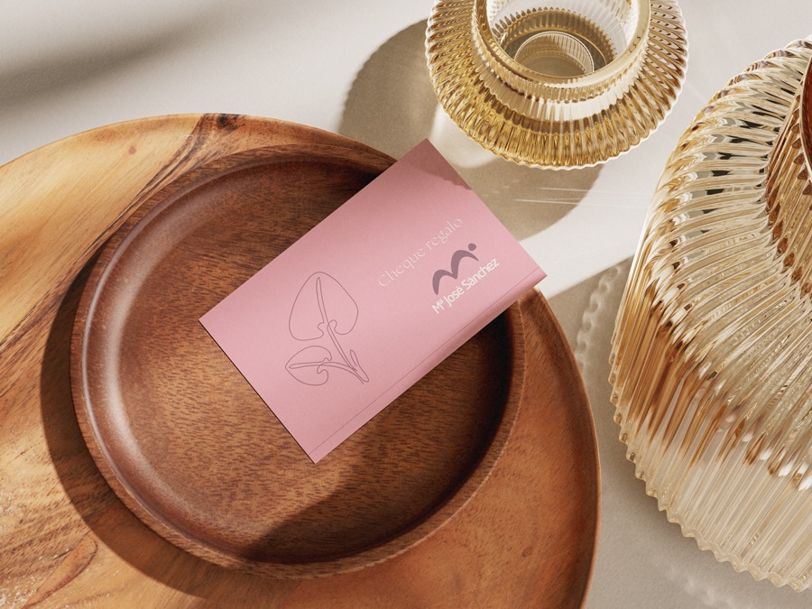 Vista desde arriba de una tarjeta regalo sobre un plato de madera, al lado de dos jarrones de cristal