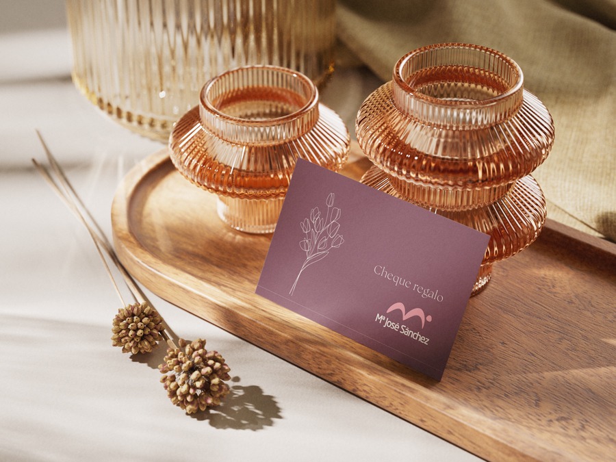 Tarjeta regalo sobre una bandeja de madera, apoyada en dos pequeños jarrones de cristal rosa