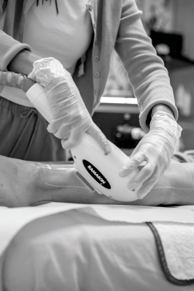 Una persona con guantes sosteniendo un aparatado sobre la espalda de otra tumbada en una camilla